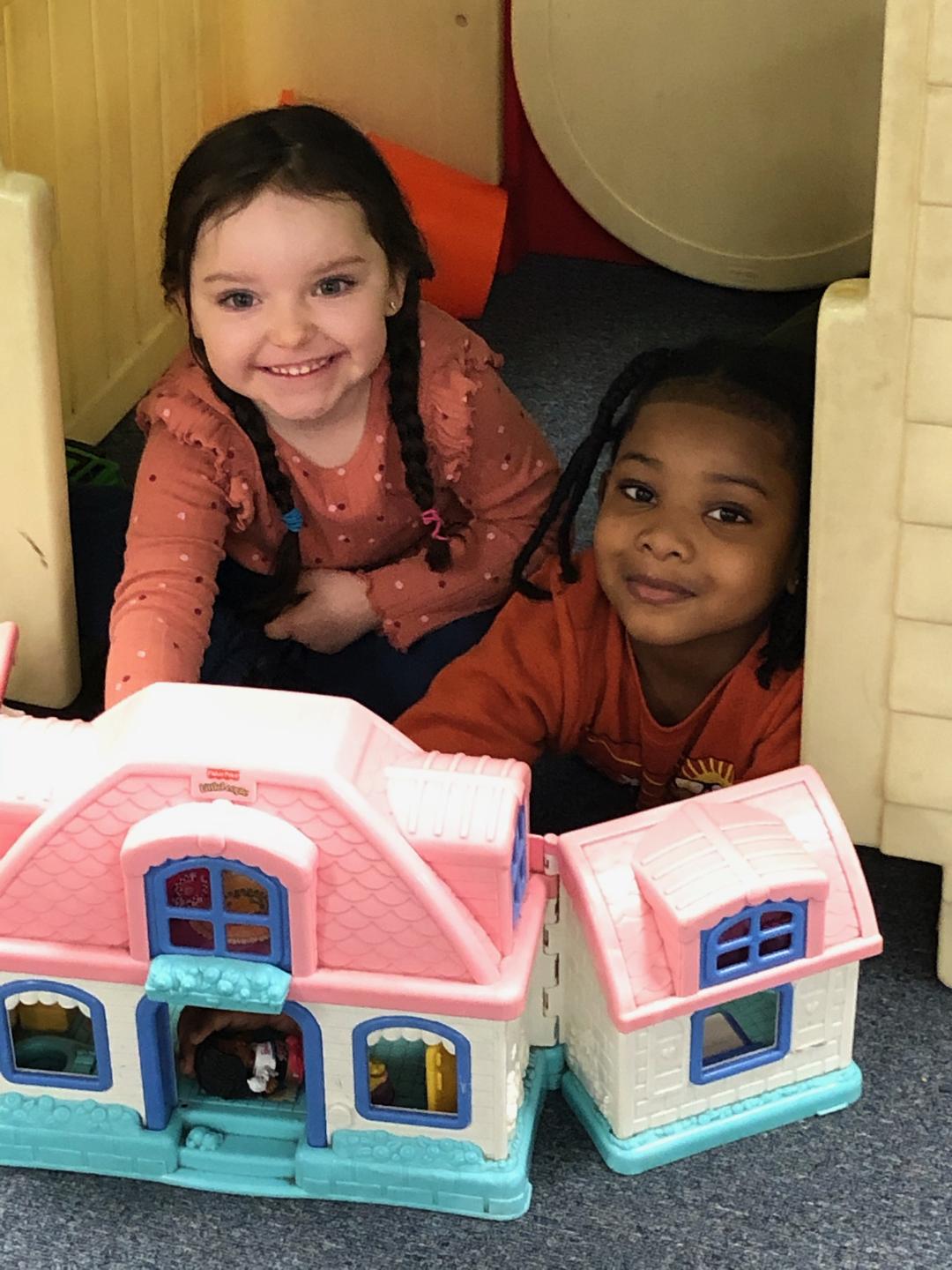 Children playing with dollhouses at Munchkinland Daycare